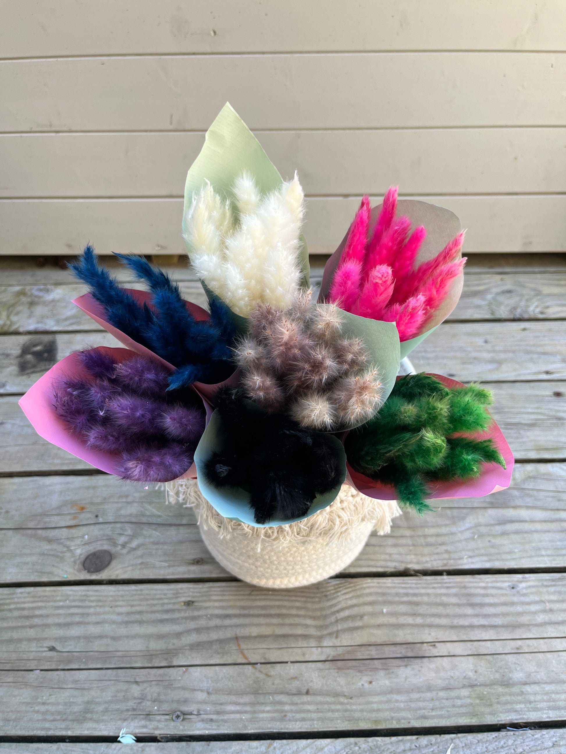 bunches of mini pampas grass wrapped in paper and displayed in a basket