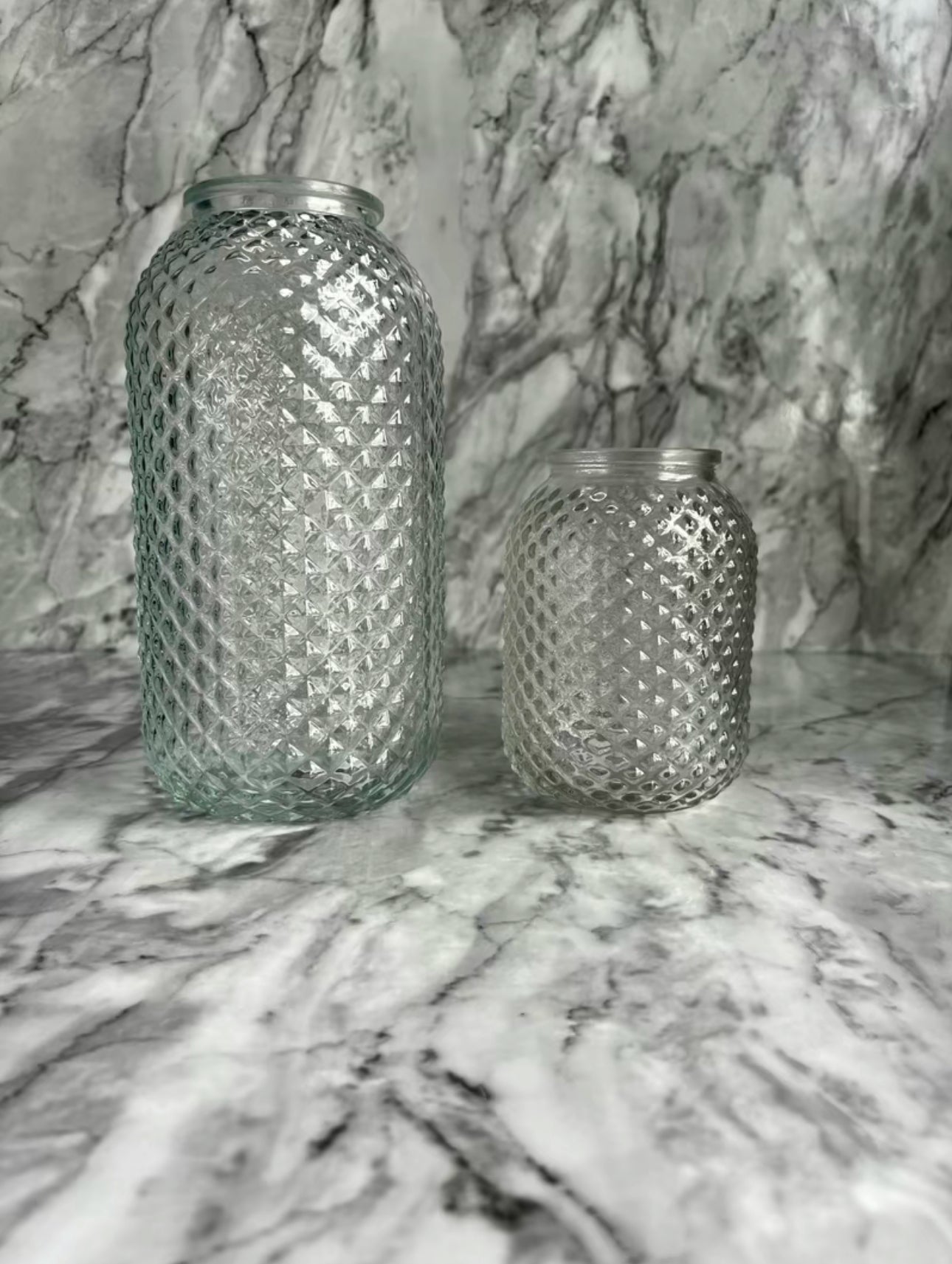 Two sizes of the clear lola vases on a table