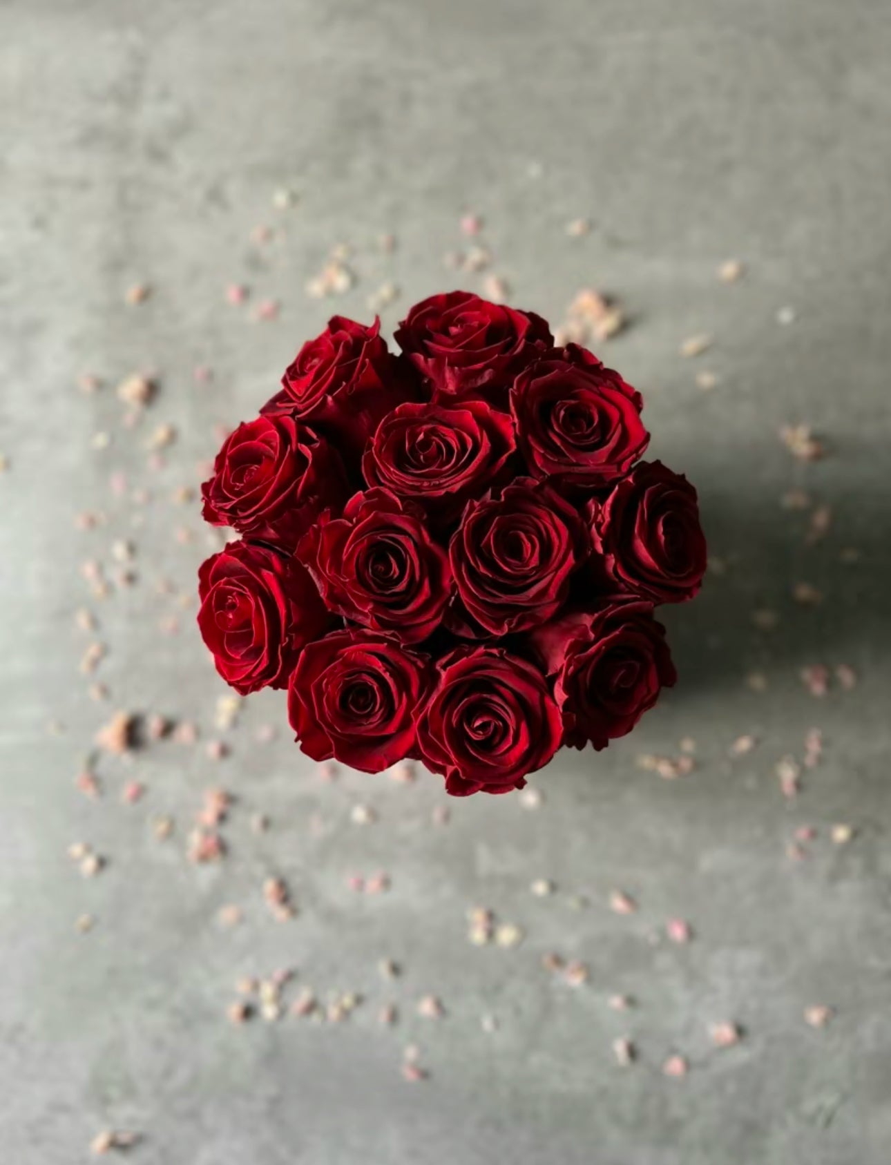 Birds eye view of Preserved dried red roses in a velour floristry hat box displayed on a table