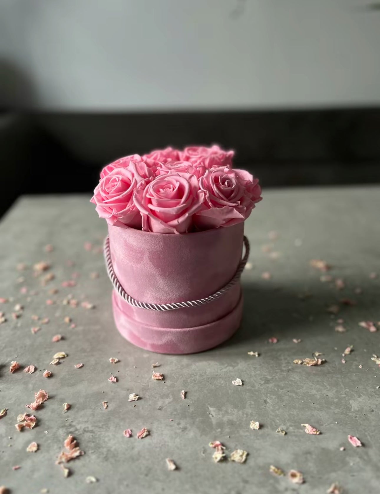 Preserved dried pink roses in a velour floristry hat box displayed on a table