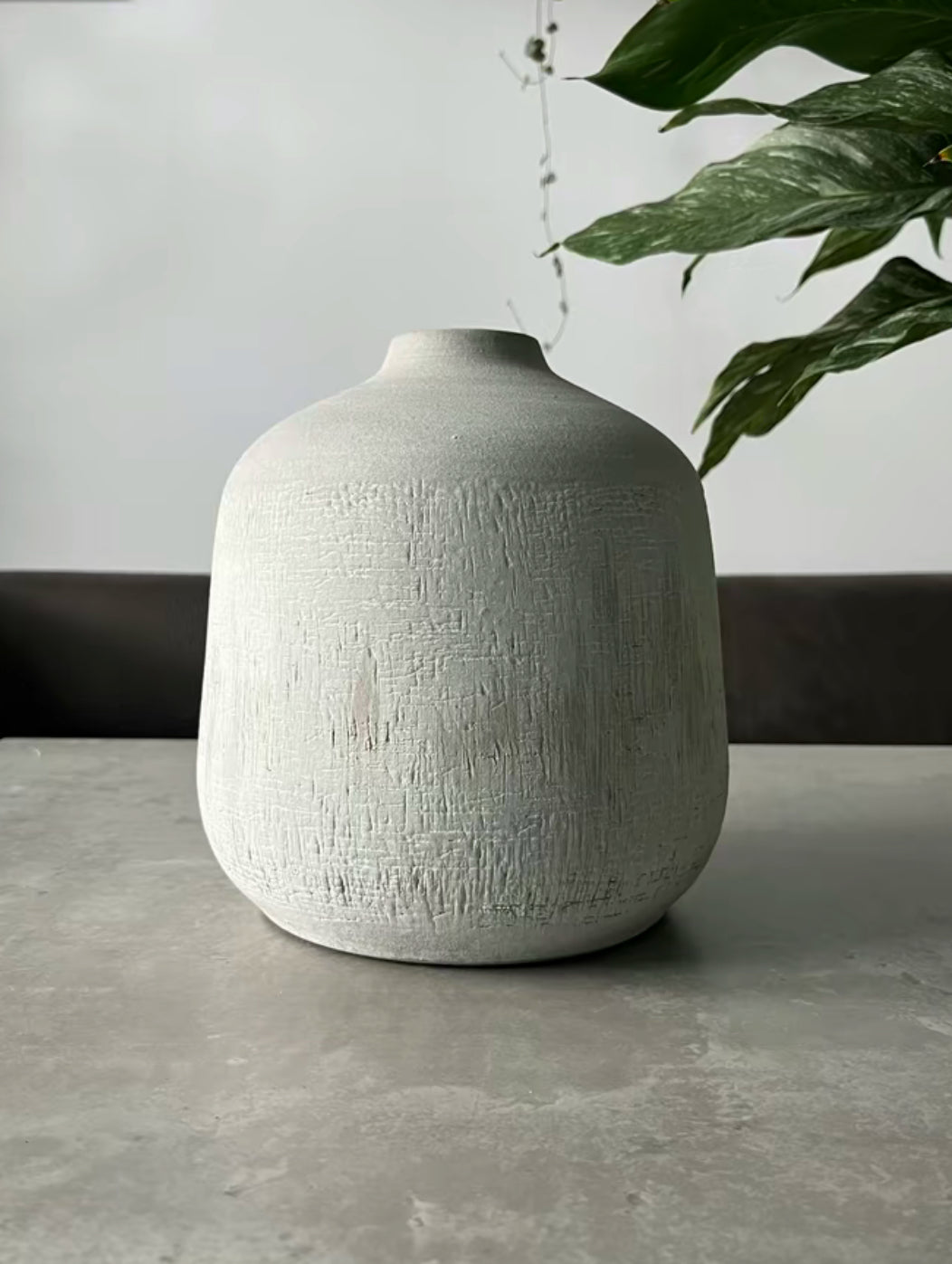 Terracotta stone colour vase in the shade grey being displayed on a table